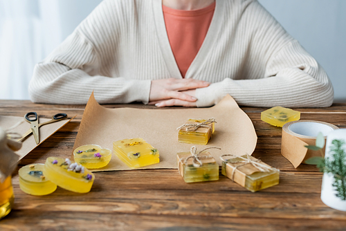 Cropped view of handmade soap on craft paper near craftswoman at home