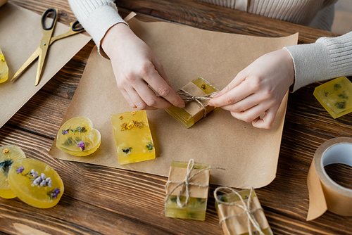 craftswoman packaging handmade soap on craft paper on table