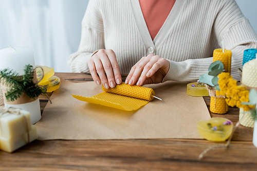 Cropped view of craftswoman making candle on craft paper at home