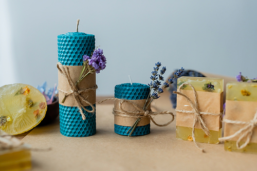 Handmade candles and soap bars with dry flowers on grey background