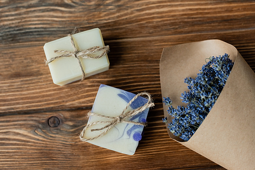 Top view of bouquet of lavender near craft soap on wooden surface