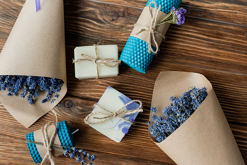 Top view of lavender flowers near handmade soap and candles on wooden surface