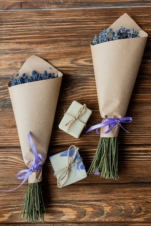 Top view of bouquets of lavender near craft soap bars on wooden surface