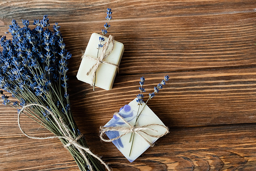 Top view of lavender flowers near handmade soap on wooden surface