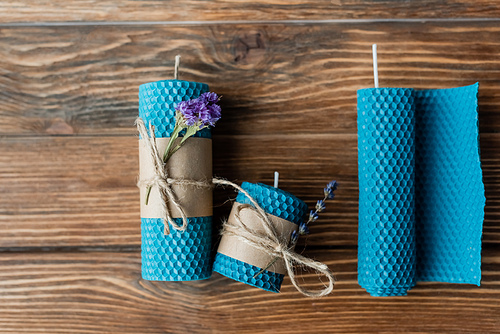 Top view of handmade wax candles with flowers on wooden surface