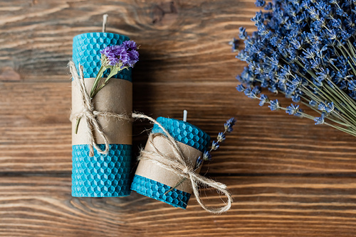 Top view of handmade candles and lavender flowers on wooden surface