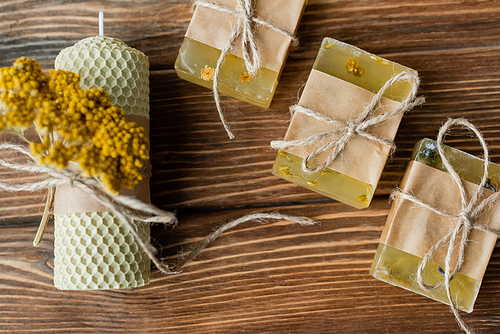 Top view of handmade candle and soap bars with twine on wooden surface