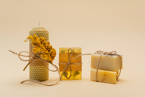 Handmade candle and soap bars with twine on beige background