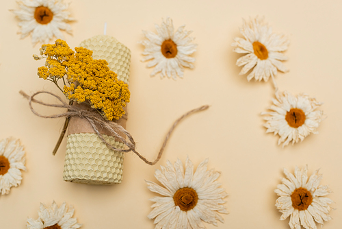 Top view of handmade candle and dry flowers on beige background