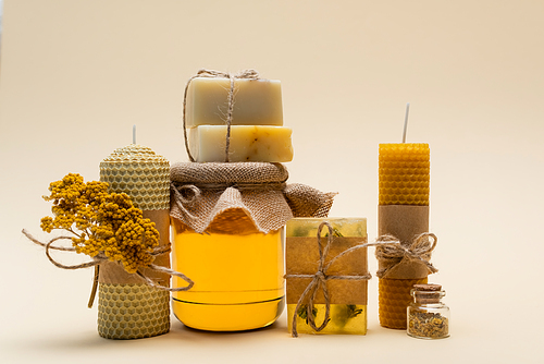 Craft soap and candles near jar with honey on beige background