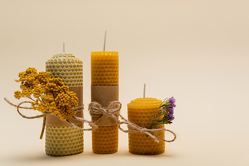 Handmade candles with dry flowers on beige background