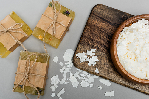 Top view of craft soap near wooden bowl and cutting board on grey background