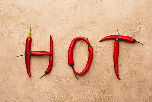 top view of word hot made of chili peppers on beige concrete surface