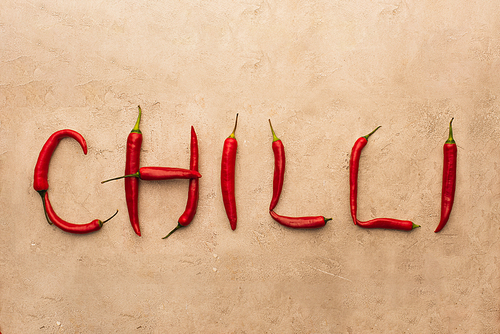 top view of word chilli made of peppers on beige concrete surface