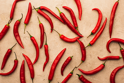 top view of scattered chili peppers on beige concrete surface