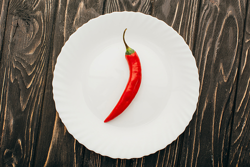 top view of red chili pepper on white plate on wooden surface