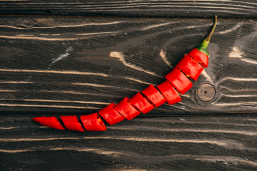 top view of sliced red chili pepper on wooden surface