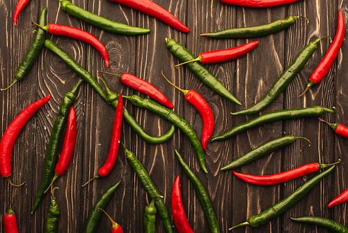 top view of red chili peppers and green jalapenos on wooden surface