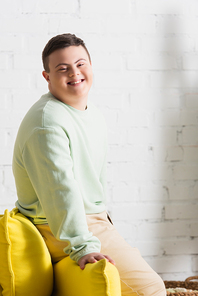 Positive teenager with down syndrome  near couch in living room