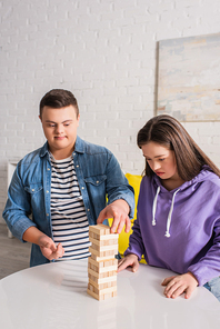 Teen friends with down syndrome playing wood blocks game at home