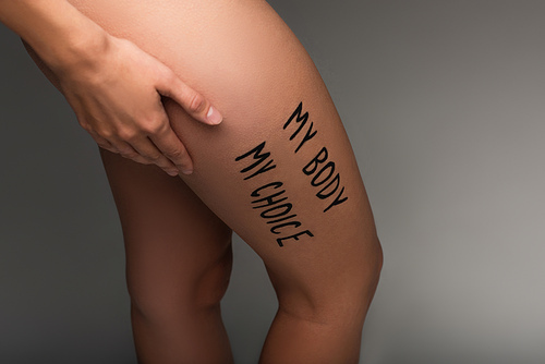 cropped view of nude woman with my body my choice lettering on hip isolated on dark grey