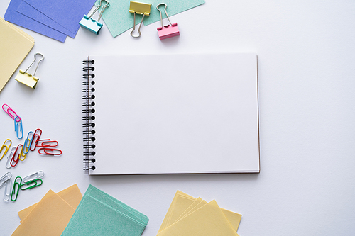 top view of blank notebook near colorful stationery on white