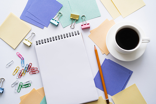 top view of cup of coffee near blank notebook and stationery on white
