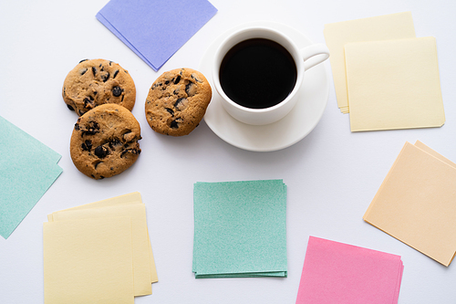 top view of chocolate chip cookies and cup of coffee near paper notes on white