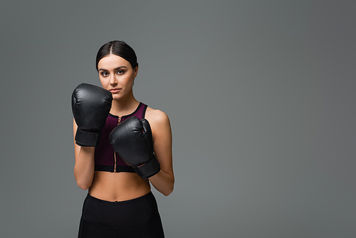 slim woman in black sportswear and boxing gloves  isolated on grey