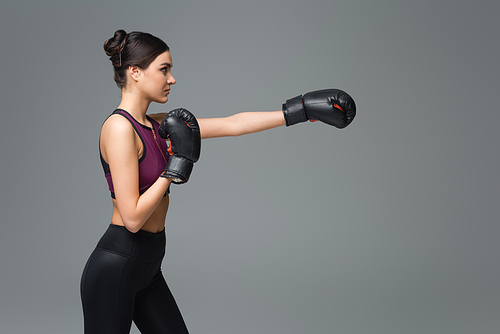 side view of woman in black sportswear boxing isolated on grey