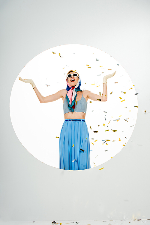 Shocked stylish woman standing under falling confetti near circle on white background