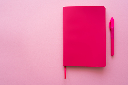 top view of bright notebook and pen on pink