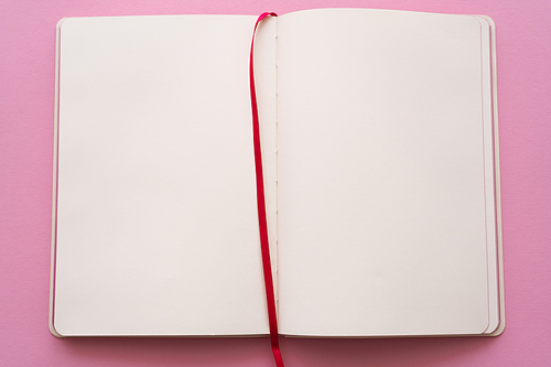 top view of open and empty notebook on pink