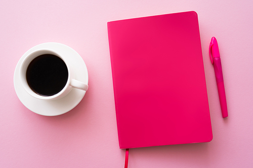 top view of pen near bright notebook and cup of coffee on pink