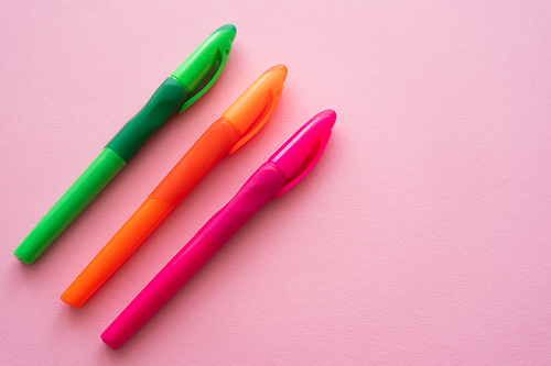 top view of colorful and bright pens on pink