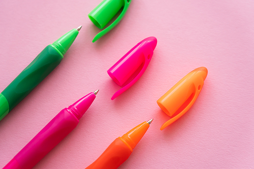 top view of bright and colorful pens on pink