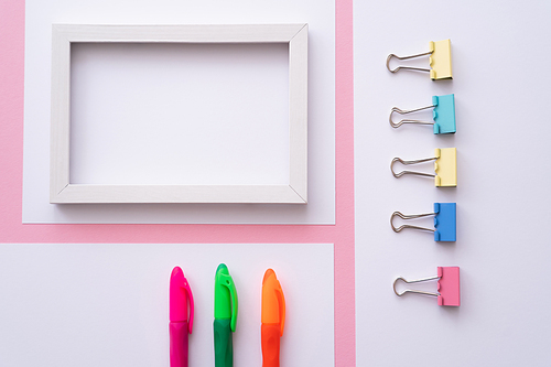 top view of colorful stationery near blank frame and papers on pink