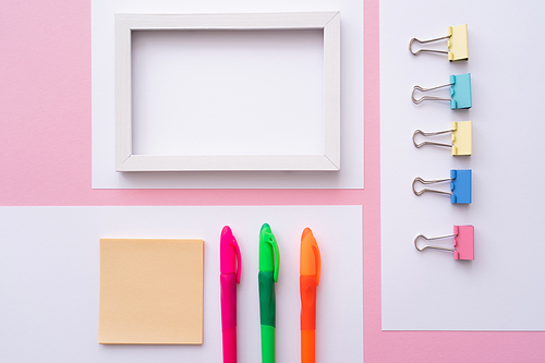 flat lay of colorful stationery near blank frame and papers on pink