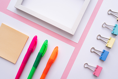 flat lay of colorful stationery near blank frame and white papers on pink