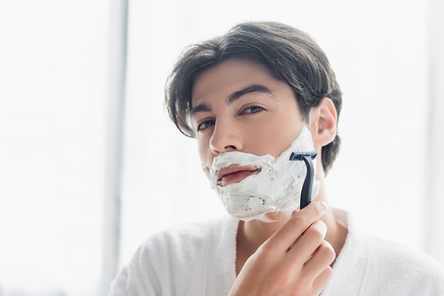 brunette man  while shaving with safety razor
