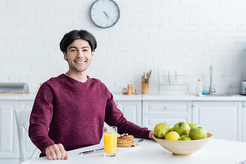 happy man  near delicious breakfast and fresh fruits in kitchen