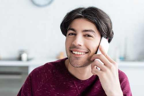 happy brunette man talking on mobile phone and  at home
