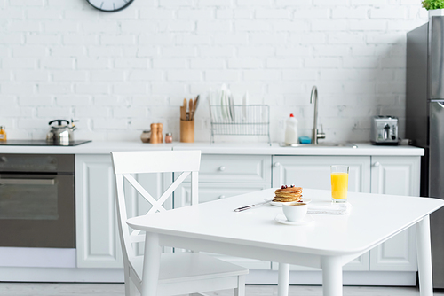 tasty pancakes, coffee and orange juice on white table in modern kitchen
