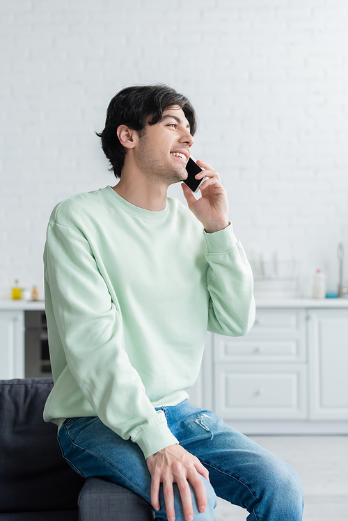 young brunette man smiling during conversation on mobile phone