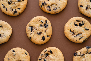 Top view of cookies with chocolate chips on brown background