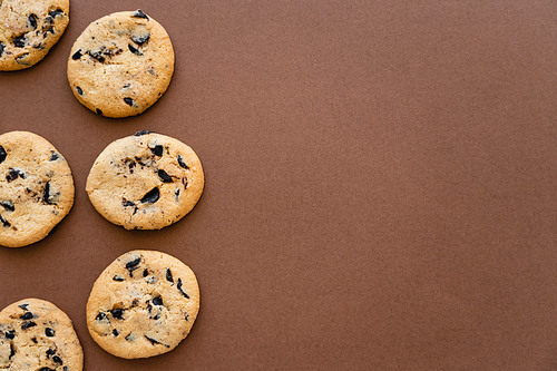 Top view of cookies with chocolate on brown background with copy space