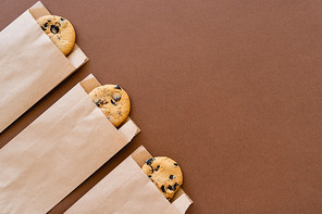 Top view of cookies in craft packages on brown background with copy space