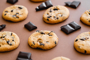 Close up view of cookies and chocolate pieces on brown background
