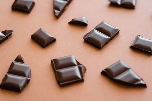 Close up view of pieces of dark chocolate on brown background