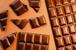 Top view of natural milk chocolate on brown background
